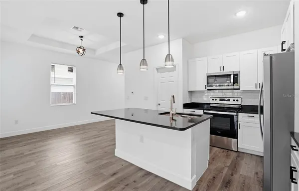 a kitchen with granite countertop a sink stove and refrigerator