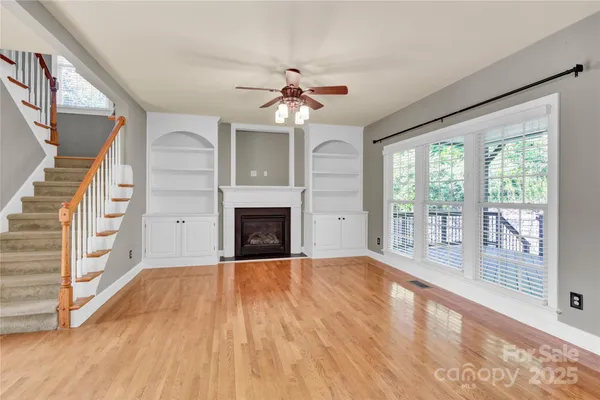 a view of empty room with wooden floor and fan