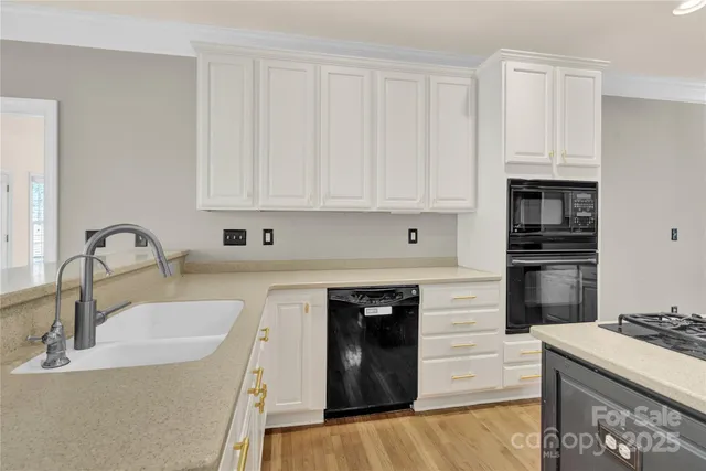 a kitchen with granite countertop a sink stainless steel appliances and white cabinets