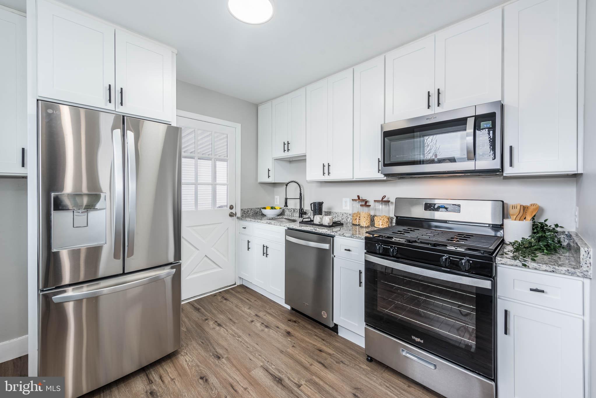 8106 Murray Point Road Dundalk, MD 21222 - Photo 5 of 32 a kitchen with cabinets stainless steel appliances and wooden floor