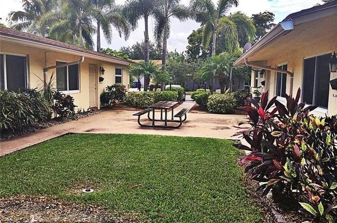 408 Northeast 12th Avenue, Unit 2 Pompano Beach, FL 33060 - Photo 4 of 14 a view of a patio with table and chairs potted plants and palm trees