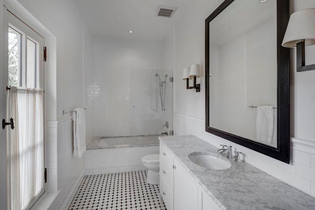 a bathroom with a granite countertop sink a toilet a mirror and shower