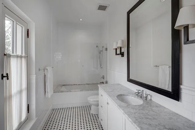 a bathroom with a granite countertop sink a toilet a mirror and shower