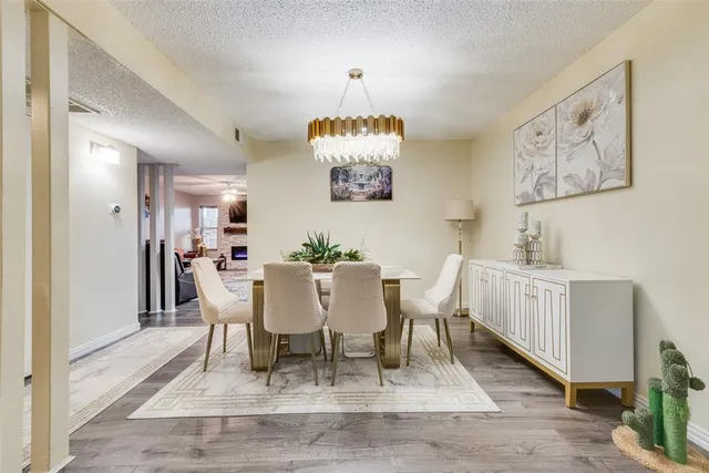 a dining room with wooden floor a chandelier a wooden table and chairs