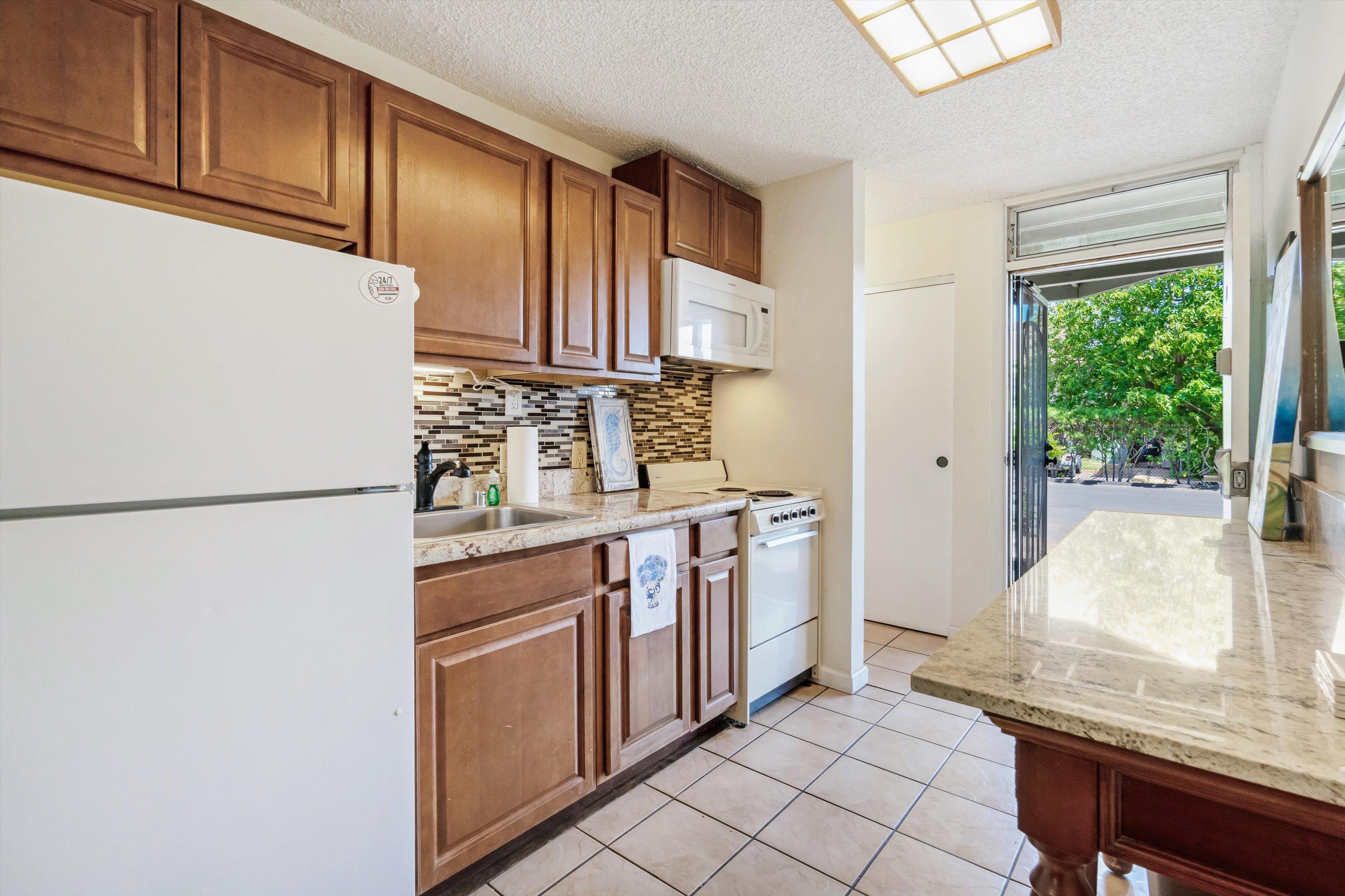 715 South Kihei Road, Unit B 120 Kihei, HI 96753 - Photo 4 of 36 a kitchen with stainless steel appliances granite countertop a refrigerator and a stove
