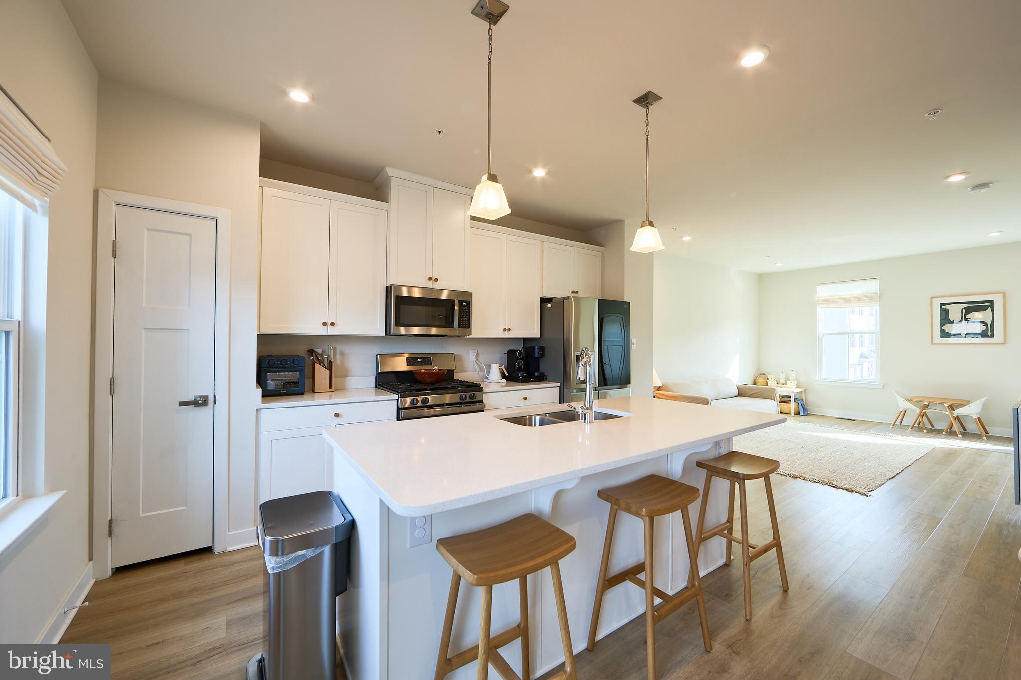 463 Paperbark Square Downingtown, PA 19335 - Photo 4 of 31 a kitchen with stainless steel appliances granite countertop a stove a refrigerator a kitchen island a dining table and chairs with wooden floor
