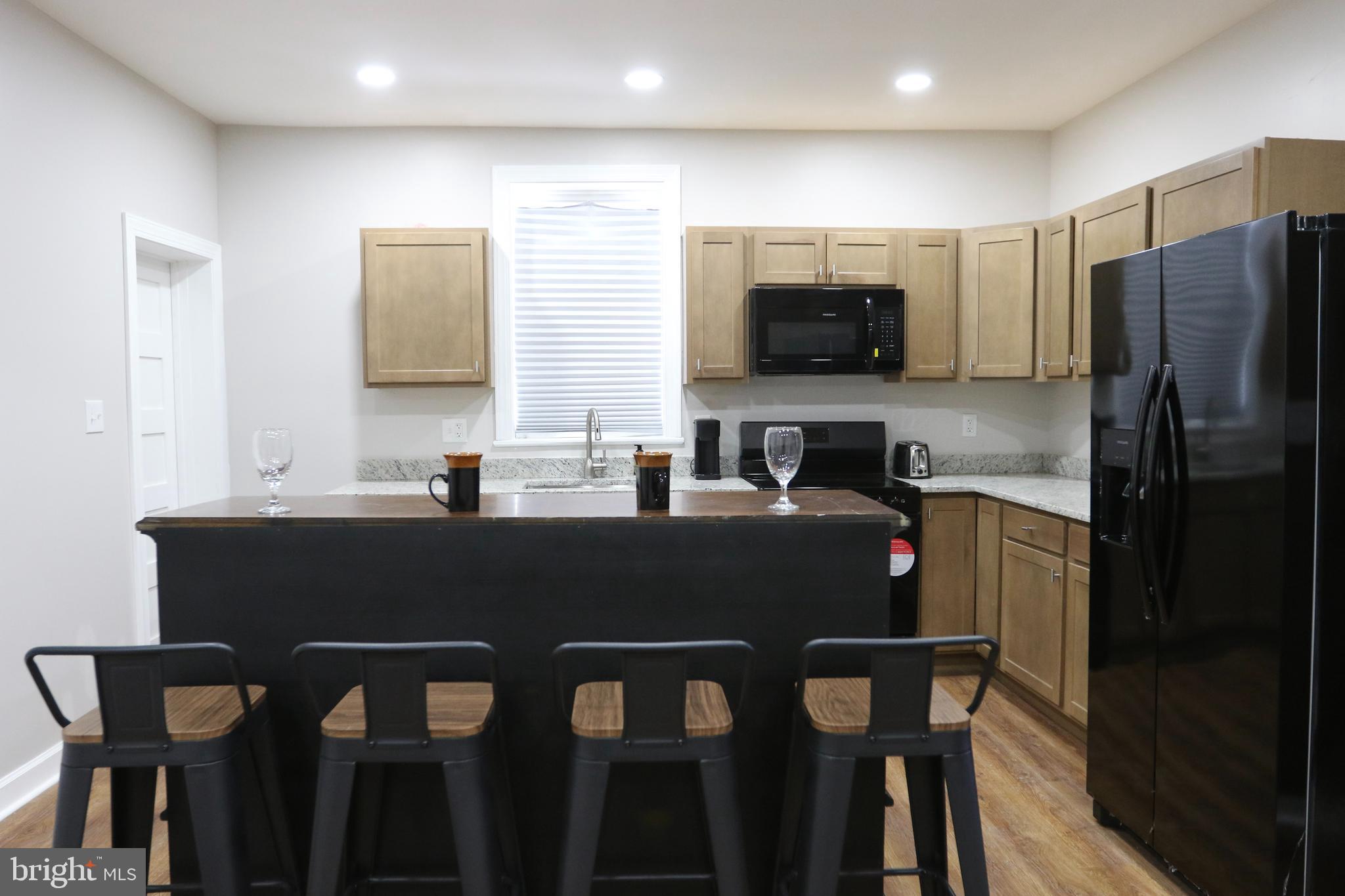 3908 Primrose Avenue Baltimore, MD 21215 - Photo 5 of 19 a kitchen with a table chairs refrigerator and microwave