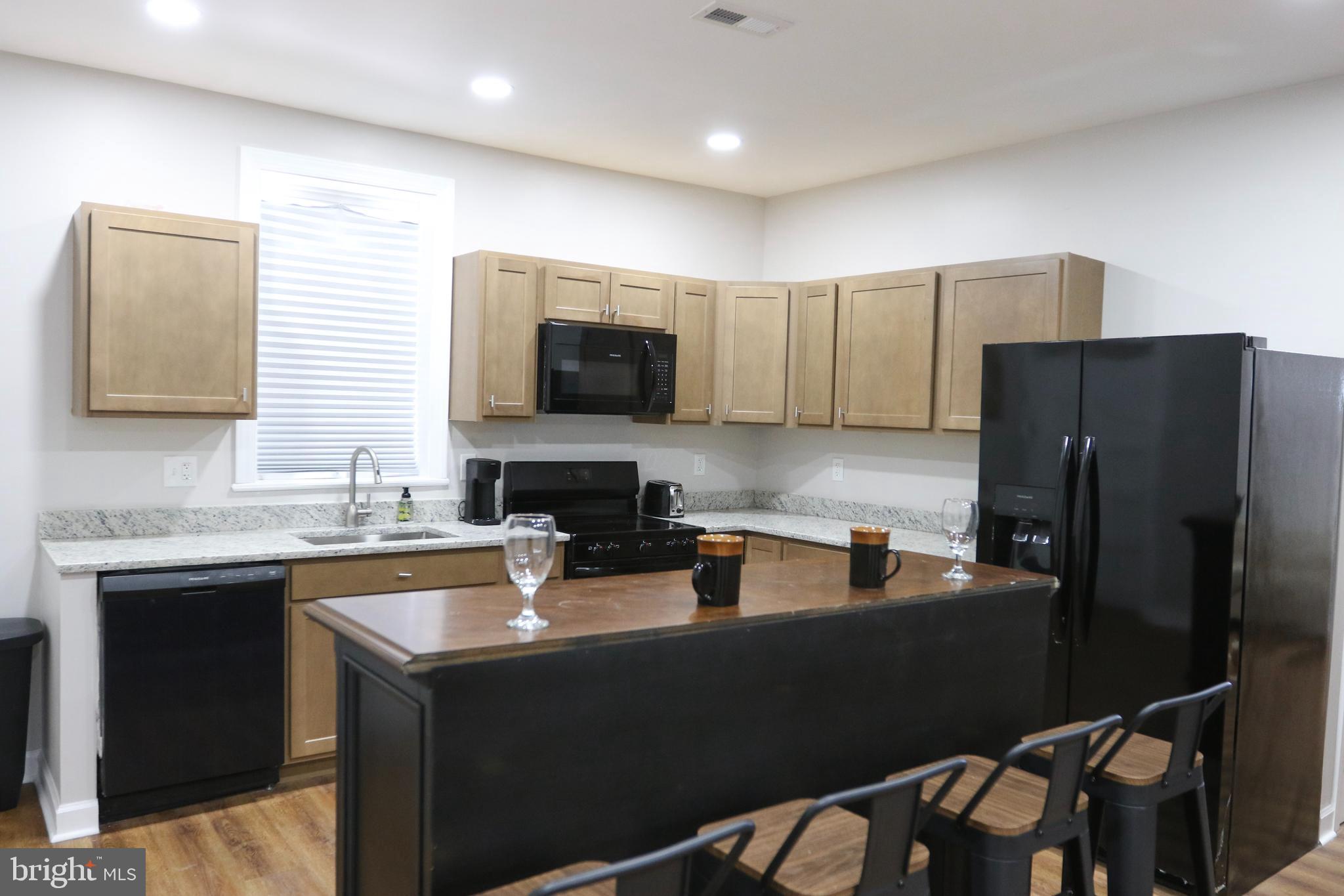 3908 Primrose Avenue Baltimore, MD 21215 - Photo 7 of 19 a kitchen with a refrigerator a sink a stove a microwave a dining table and chairs