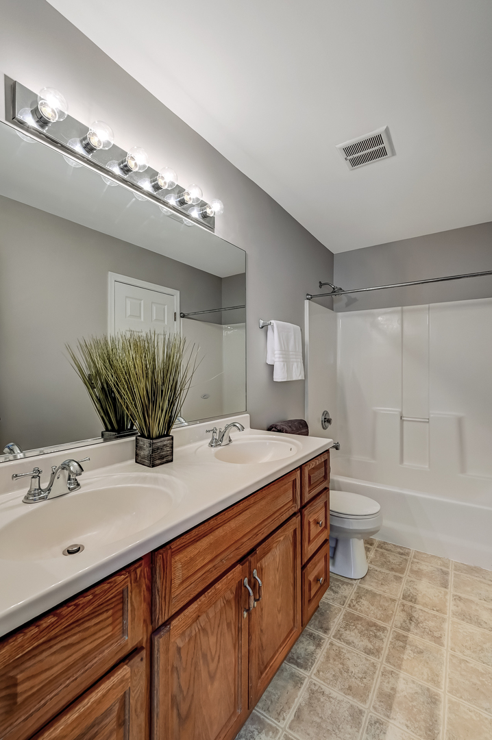 118 Enclave Circle, Unit C Bolingbrook, IL 60440 - Photo 17 of 27 a bathroom with a granite countertop sink a toilet and bathtub