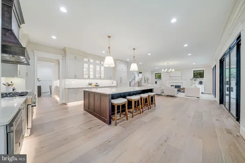 a large kitchen with a large counter top a sink stainless steel appliances and cabinets