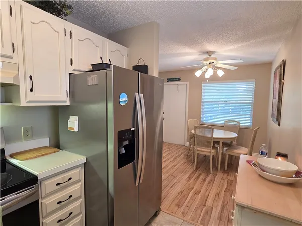 a kitchen with stainless steel appliances a stove a refrigerator a dining table and chairs with wooden floor