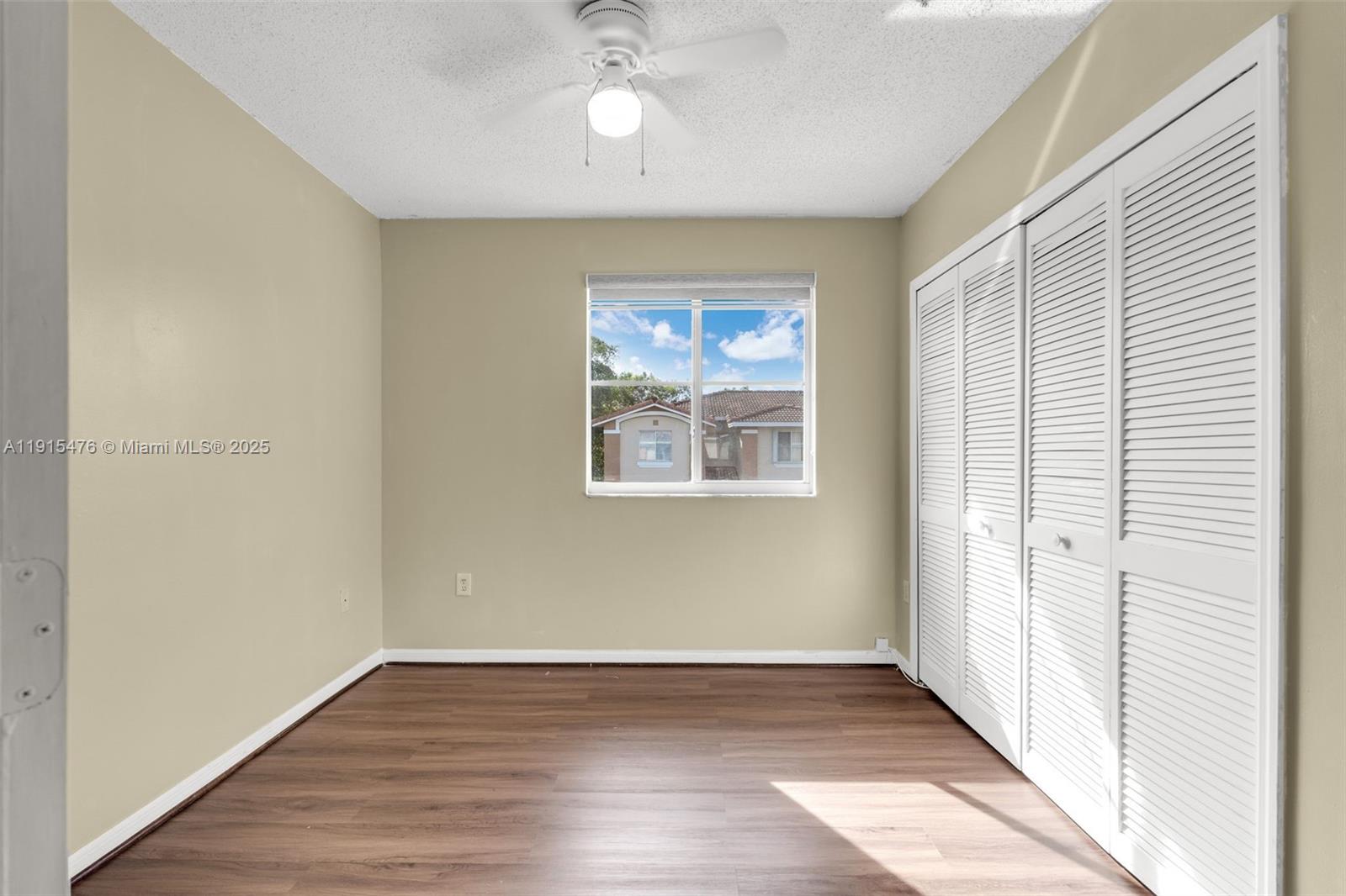 6263 Southwest 139th Avenue Miami, FL 33183 - Photo 18 of 38 an empty room with wooden floor chandelier fan and windows