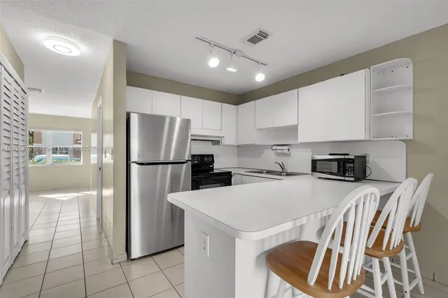 a kitchen with a sink a refrigerator and a stove top oven