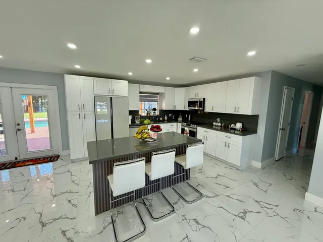 a kitchen with stainless steel appliances granite countertop a refrigerator and a stove top oven with white cabinets