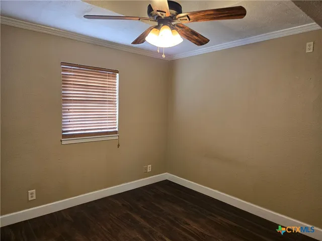 a view of an empty room with window and chandelier fan