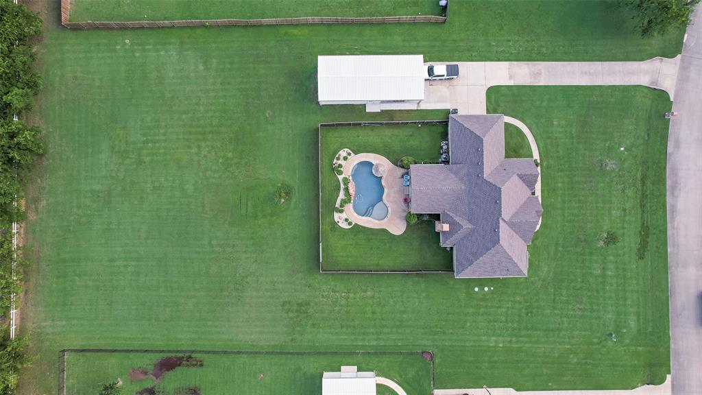 1132 Chartres Street Kaufman, TX 75142 - Photo 23 of 25 Spacious property featuring an irregular-shaped swimming pool with stone coping, mature trees, a detached carport, and extensive lawn areas