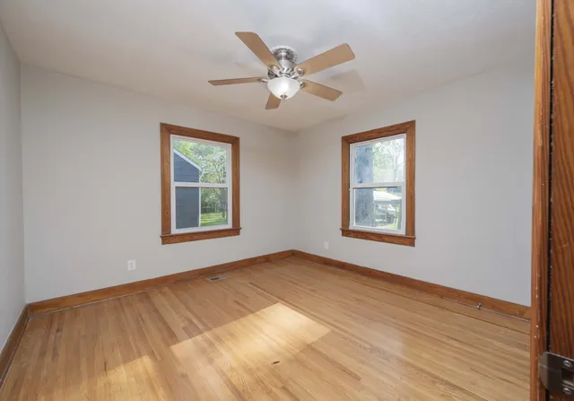 a view of an empty room with window and wooden floor