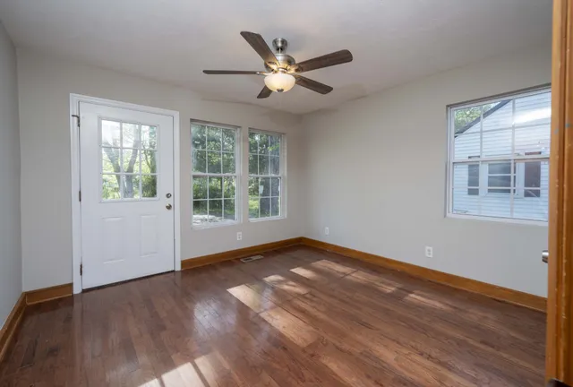 a view of an empty room with wooden floor and a window