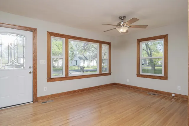 a view of an empty room with wooden floor and a window