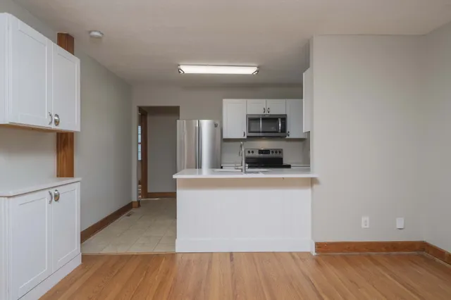 a kitchen with wooden floors and white cabinets