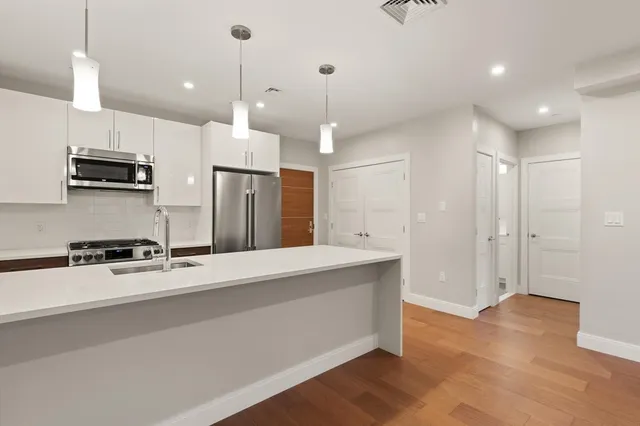 a kitchen with kitchen island a sink stainless steel appliances and wooden floor