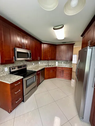 a large kitchen with granite countertop a stove microwave and refrigerator