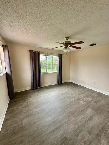 an empty room with a ceiling fan and window
