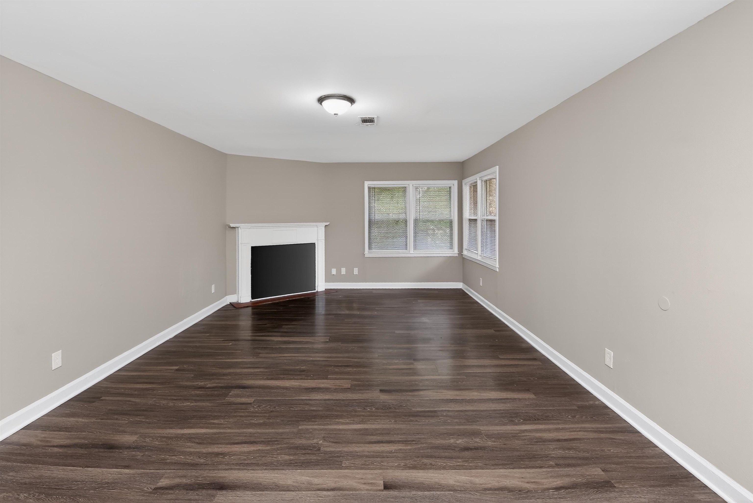 318 East Raines Road Memphis, TN 38109 - Photo 16 of 28 Living area featuring dark wood-finish flooring, light neutral wall paint, white trim, a corner fireplace with a white mantel, and multiple windows for natural light