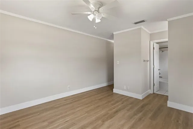 an empty room with wooden floor and a ceiling fan