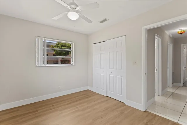 a view of an empty room with wooden floor and a ceiling fan
