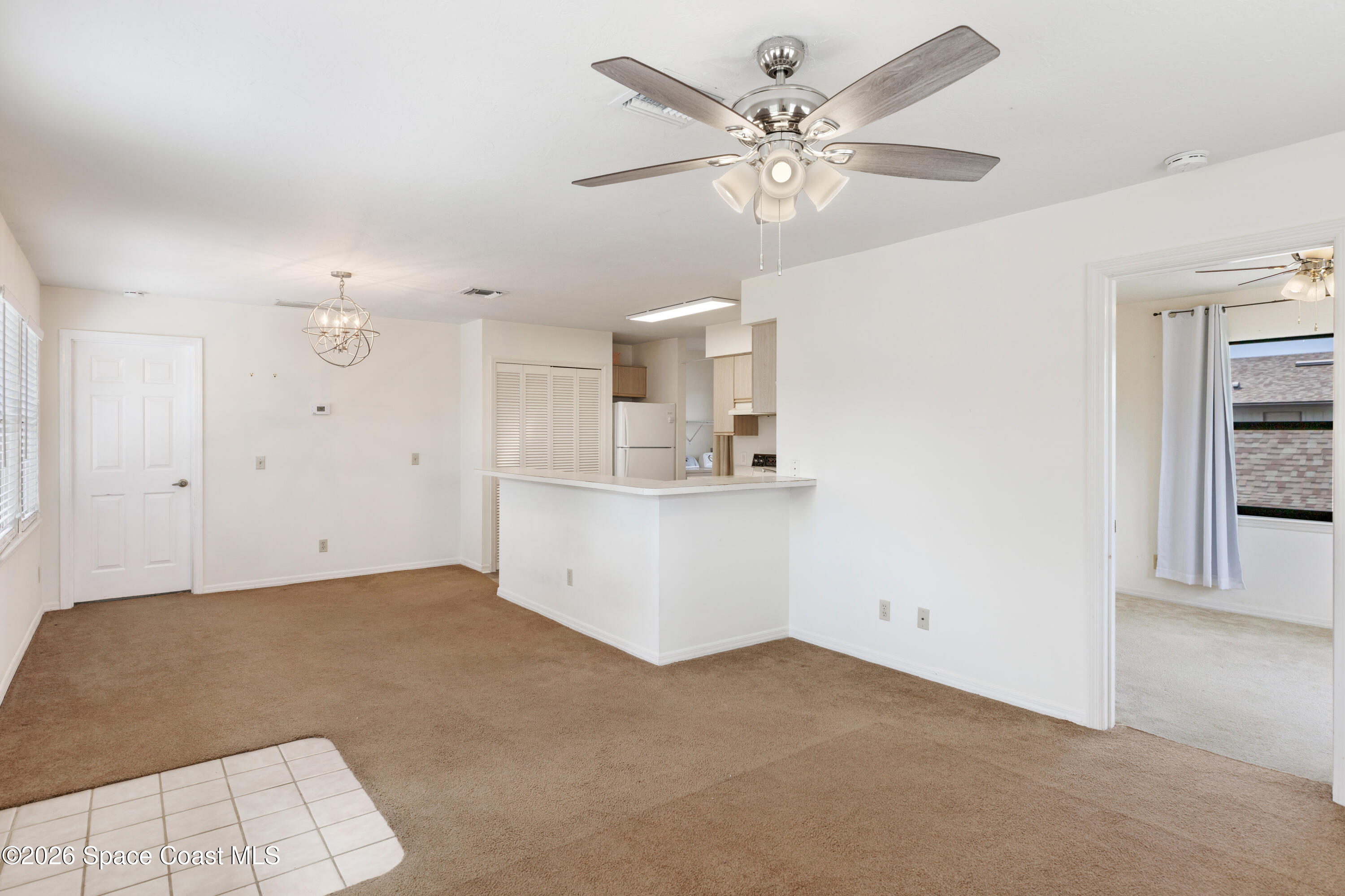 654 Centre Court Southwest, Unit 201 Vero Beach, FL 32962 - Photo 4 of 20 a view of a livingroom with a chandelier fan and kitchen view