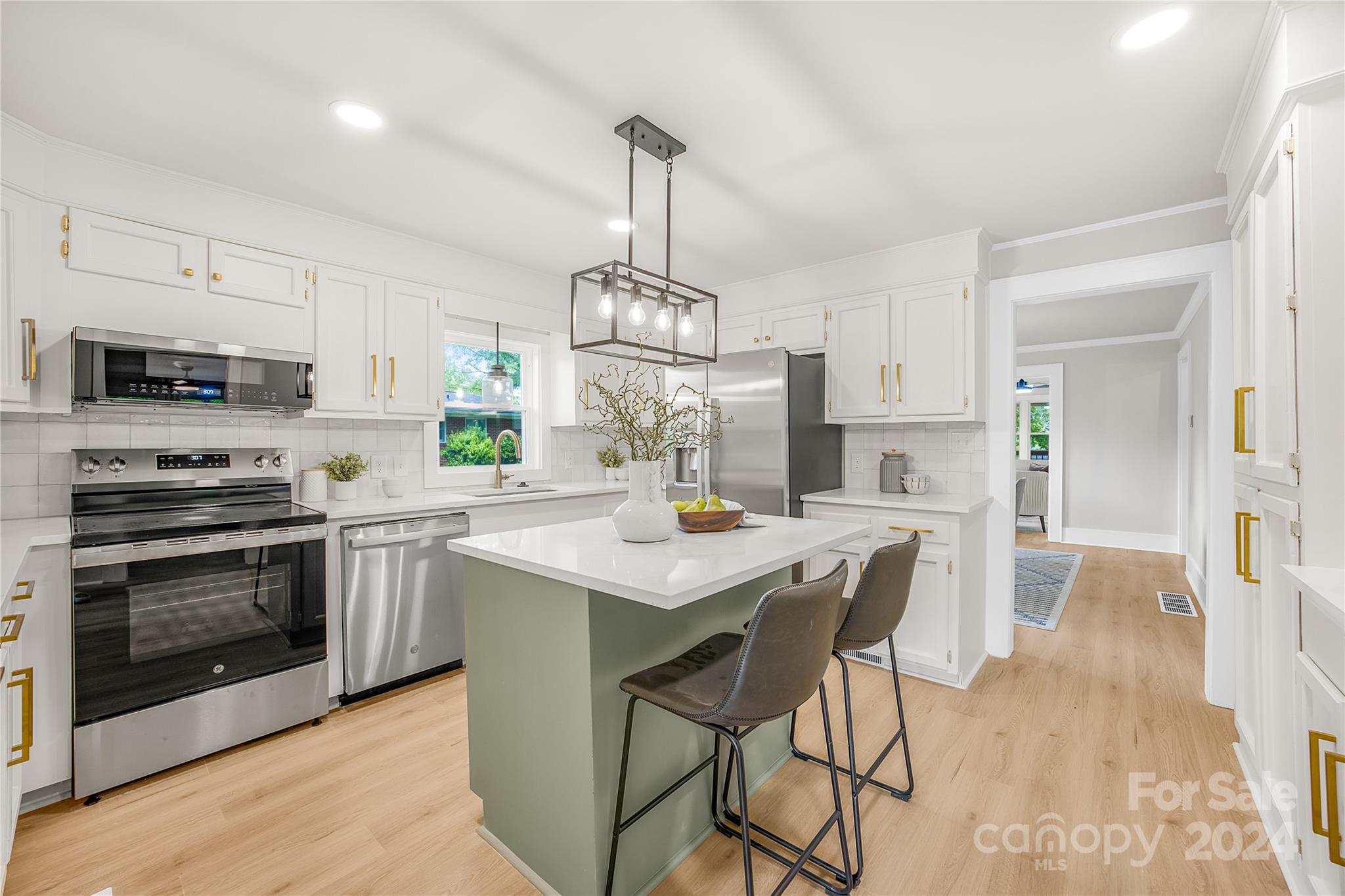 311 Roy Eaker Road Cherryville, NC 28021 - Photo 9 of 23 a kitchen with stainless steel appliances a stove a sink island a stove a refrigerator cabinets and a dining table with wooden floor