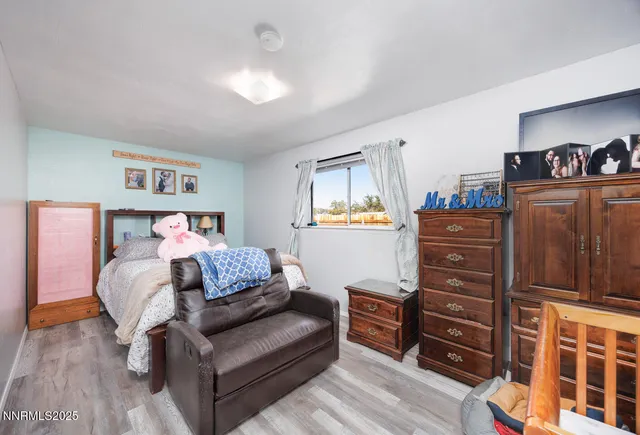a bedroom with a bed and dresser with wooden floor