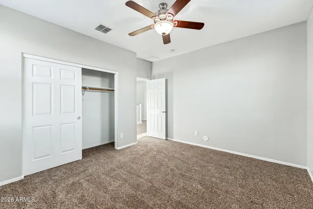an empty room with windows and chandelier fan