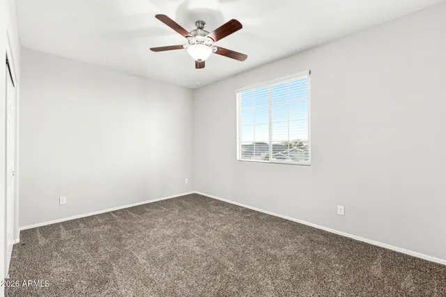 an empty room with windows and fan