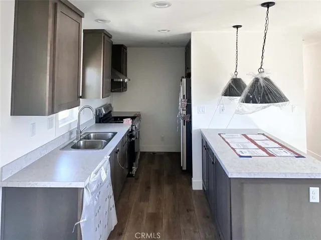 a kitchen that has a sink a stove and a wooden floor