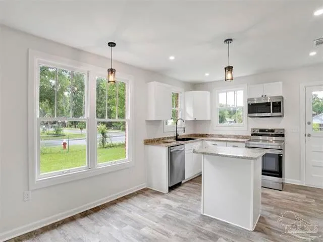 a kitchen with stainless steel appliances kitchen island a sink a stove a refrigerator cabinets and a window