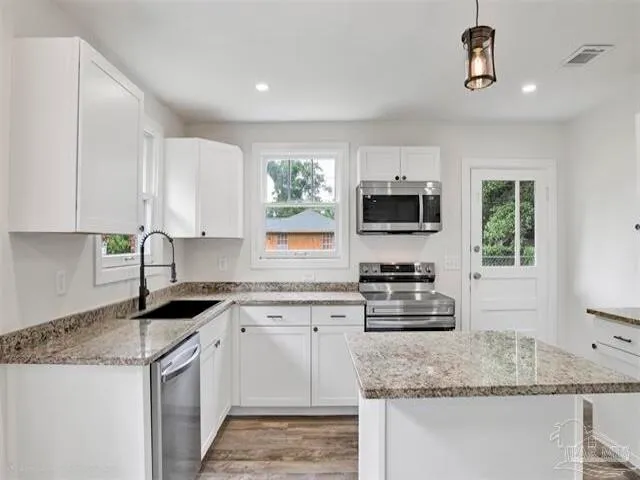 a kitchen with granite countertop a stove sink and microwave