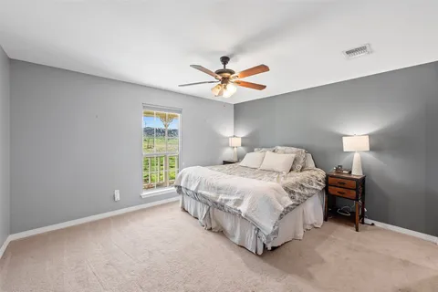 a spacious bedroom with a bed and a ceiling fan in it