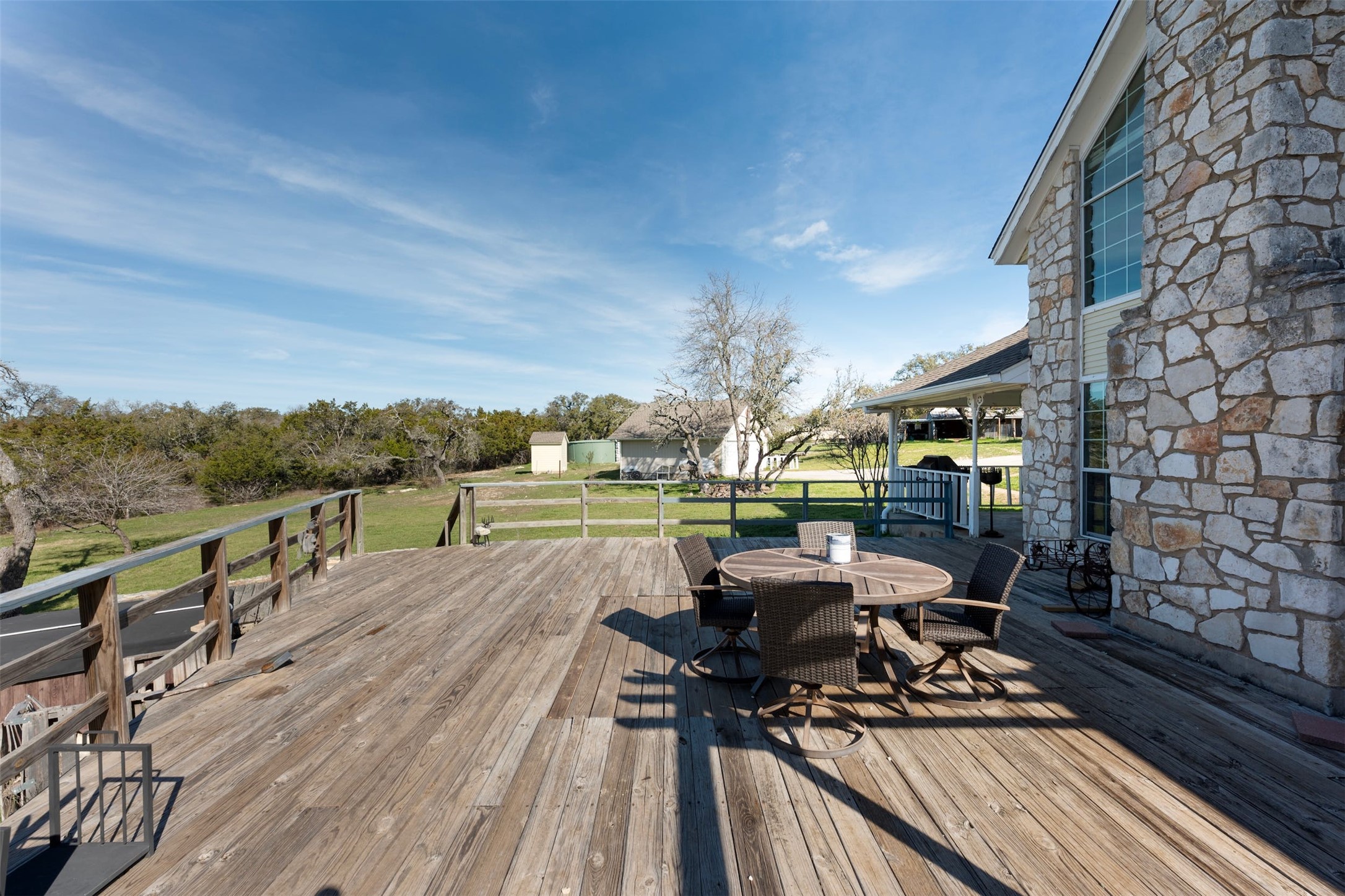 31305 Ranch Road 12 Dripping Springs, TX 78620 - Photo 27 of 32 a view of a patio with dining table and chairs with wooden floor