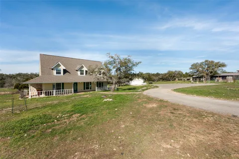 a view of a big house with a big yard and large trees