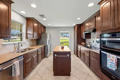 a kitchen with kitchen island granite countertop a sink counter top space appliances and cabinets
