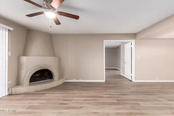a view of a livingroom with a fireplace a ceiling fan and wooden floor