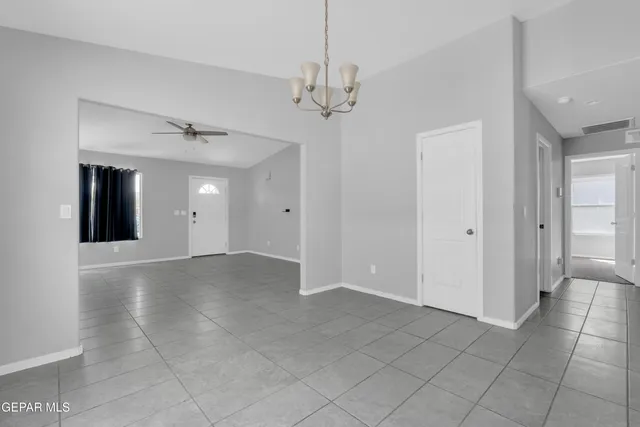 a view of an empty room with a chandelier fan