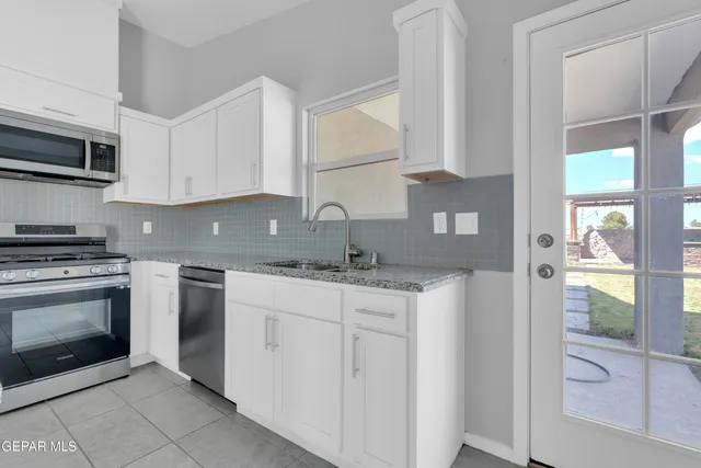 a kitchen with stainless steel appliances granite countertop a stove a sink and a microwave