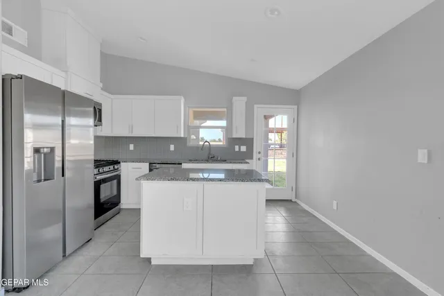 a kitchen with stainless steel appliances granite countertop a refrigerator and a stove