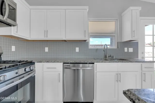 a kitchen with granite countertop white cabinets and white appliances