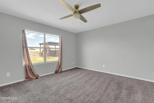 an empty room with windows and ceiling fan