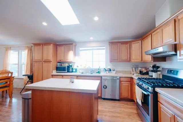 a kitchen with stainless steel appliances a stove a sink a refrigerator and cabinets
