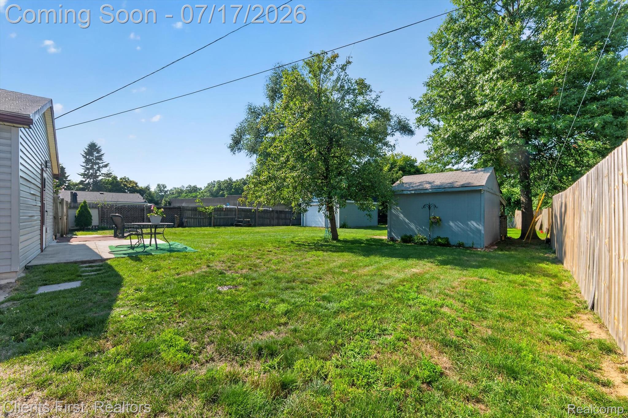 36852 Chase Street Romulus, MI 48174 - Photo 31 of 40 Expansive grassy yard featuring a concrete patio, a wooden privacy fence, and a storage shed with siding